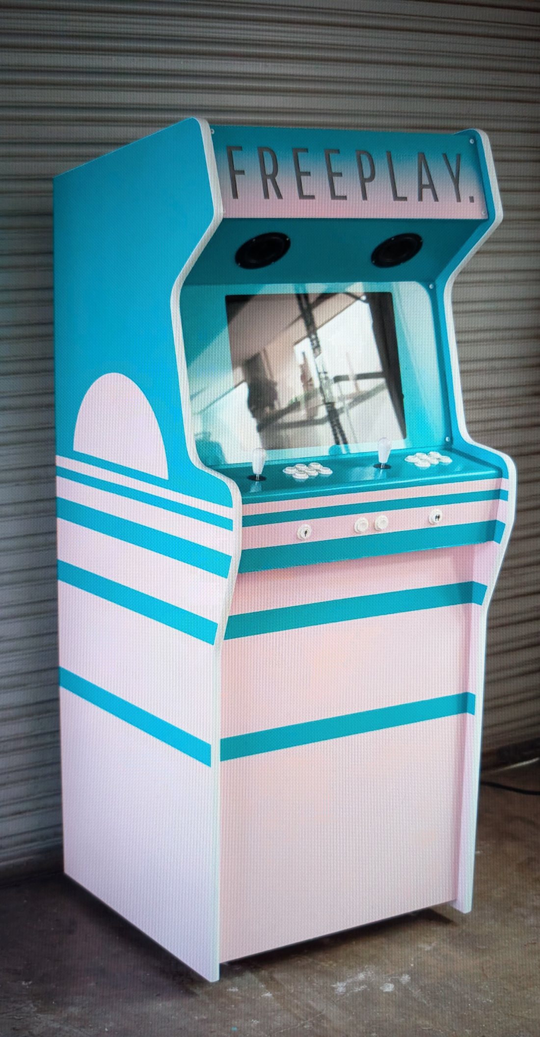 Custom upright arcade cabinet in teal and pink with a FREEPLAY marquee