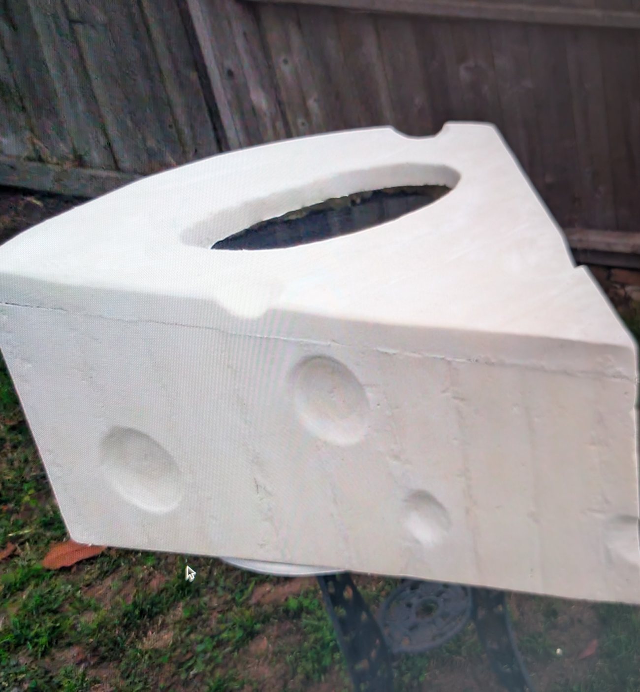 Oversized foam wedge of swiss cheese built as a prop, standing on grass