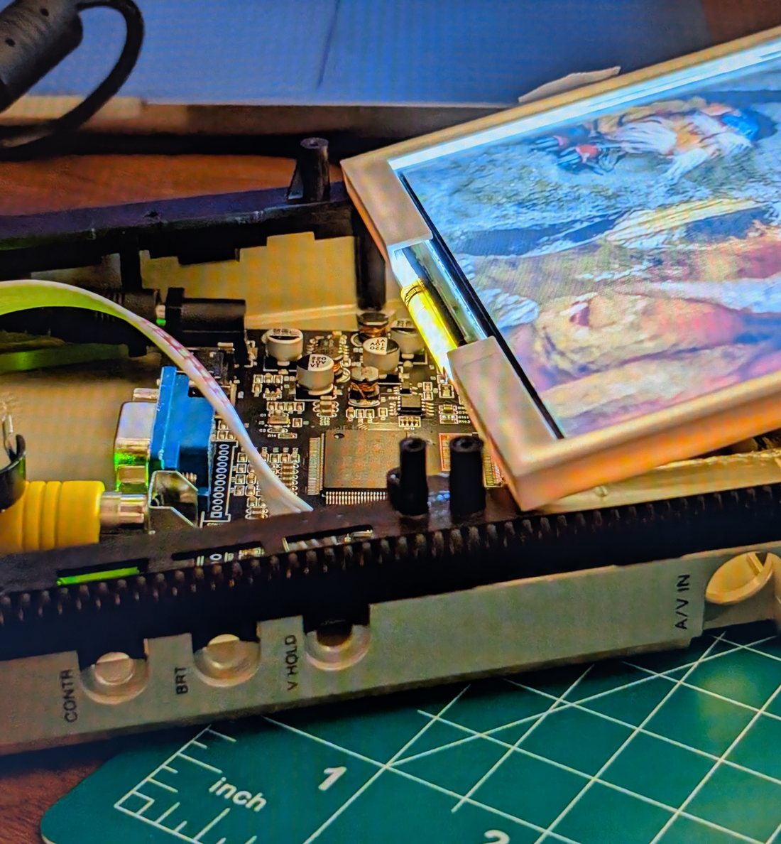 Portable Watchman television opened on a cutting mat, board exposed beside a lit colour screen