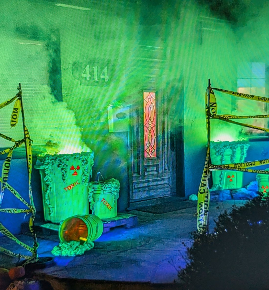 Porch dressed as a toxic waste site, green fog pouring from barrels behind caution tape